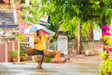 Louangphabang, Laos - 11 Ocak 2017: sokakta yürürken bir kadın sepetleri ile. Metin için yer kopyalayın.