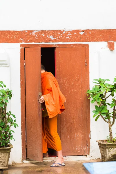 ラオスの修道士 Louangphabang、ラオスで建物に入る。テキストのためのスペースにコピーします。垂直方向. — ストック写真