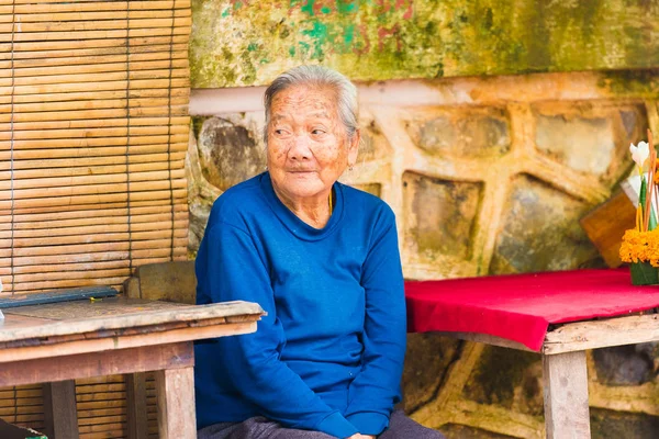 LOUANGPHABANG, LAOS - JANUARY 11, 2017: An elderly woman is sitting at a table. Copy space for text. — Stock Photo, Image