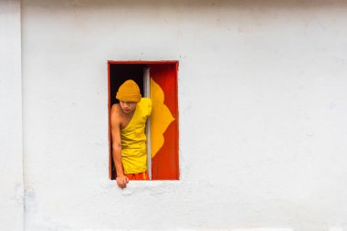 LOUANGPHABANG, LAOS - JANUARY 11, 2017: Monk in the window of the temple. Copy space for text.                                  clipart