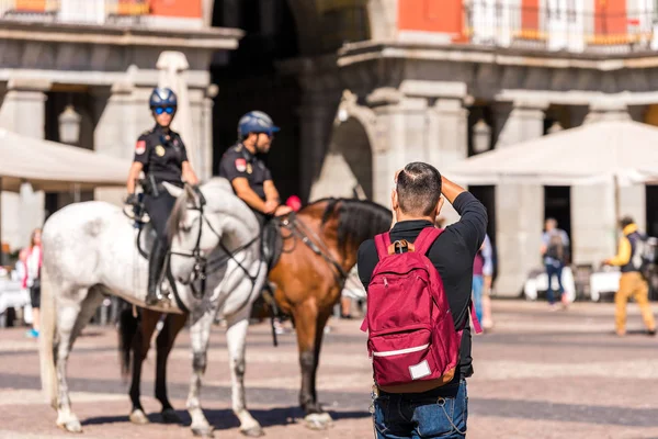 МАДРИД, Испания - 26 сентября 2017 года: Мужчина фотографирует конную полицию на площади здания Королевского дворца . — стоковое фото