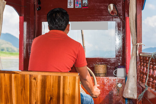 Водитель лодки у руля, Луангфабанг, Лаос. Крупный план. Вид сзади
.