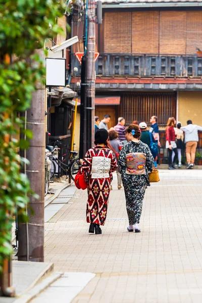 Two japanese women in a kimono on a city street in Kyoto, Japan. Back view. Copy space for text. Vertical. — Stock Photo, Image
