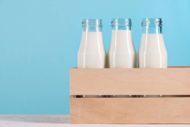 glass bottles with milk in wooden box clipart