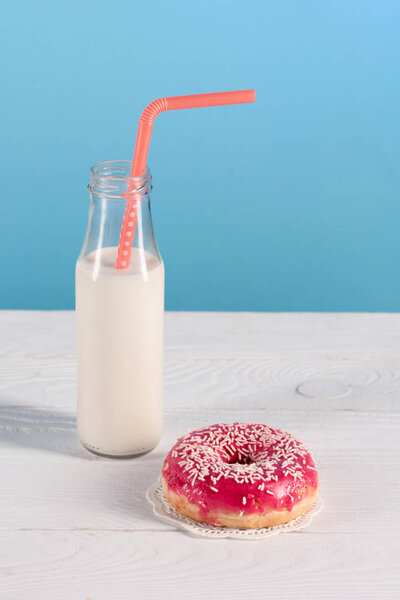 glass bottle of milk with donut on plate