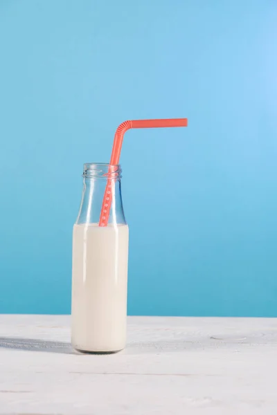 Glass bottle of milk with straw — Stock Photo, Image