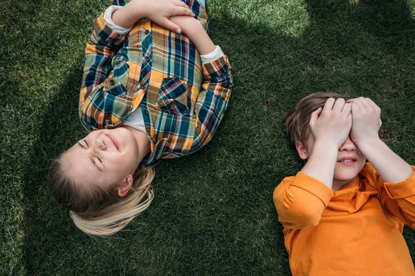 Schattige kinderen zonnebaden terwijl liggen op gras — Stockfoto