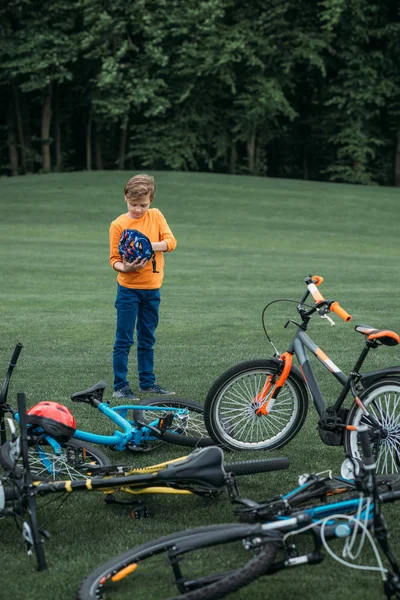 Kid boy standing near bicycles at park — Free Stock Photo