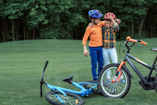 kids in helmets standing near bicycles at park