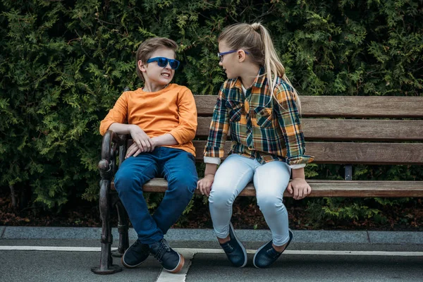 Niños sentados en el banco en el parque —  Fotos de Stock