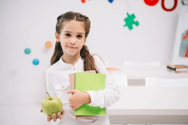 Schoolgirl with apple and textbooks — Stock Photo, Image