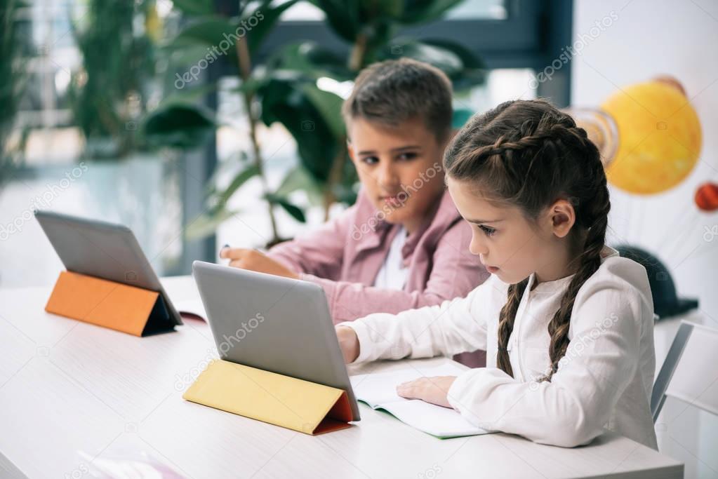 Schoolkids studying with digital tablets