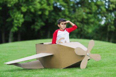 Boy playing with plane in park clipart