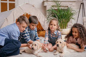 multiethnische Kinder mit Labrador-Welpen