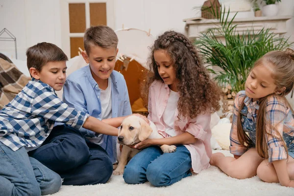 Crianças multiétnicas com filhote de cachorro labrador — Fotografia de Stock