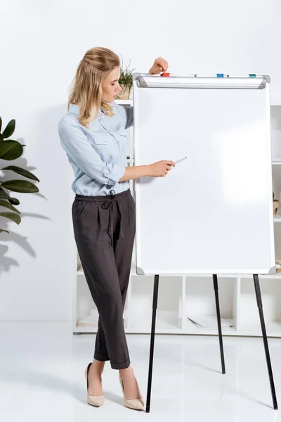 Businesswoman pointing at white board — Stock Photo, Image