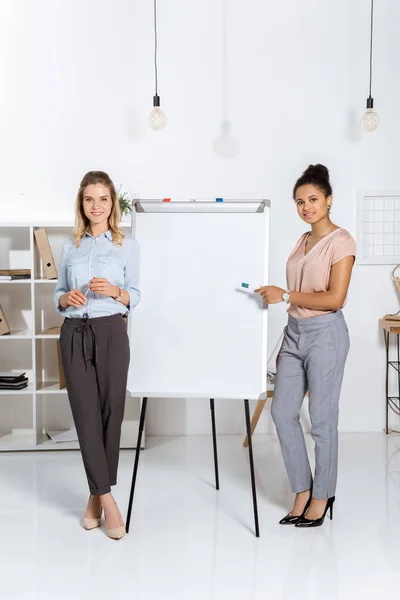 Multicultural businesswomen near white board — Stock Photo, Image