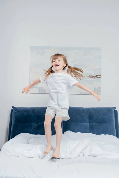 Cheerful girl jumping on bed — Stock Photo, Image