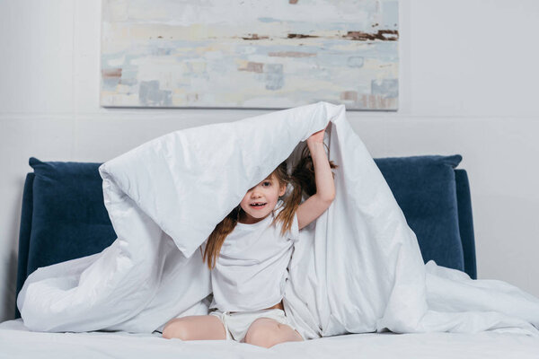 girl hiding under blanket