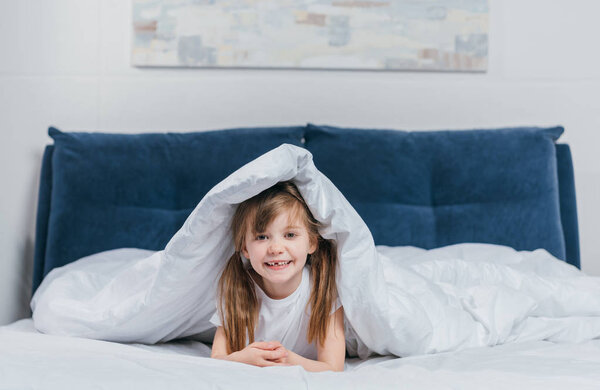 girl hiding under blanket