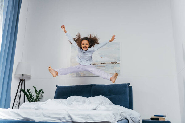 african american girl jumping on bed