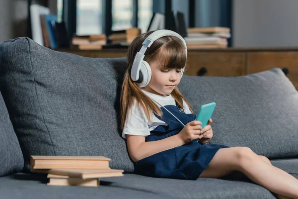 Menina em fones de ouvido usando smartphone — Fotografia de Stock