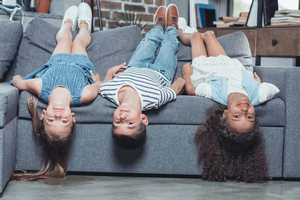 Crianças multiétnicas deitadas no sofá — Fotografia de Stock