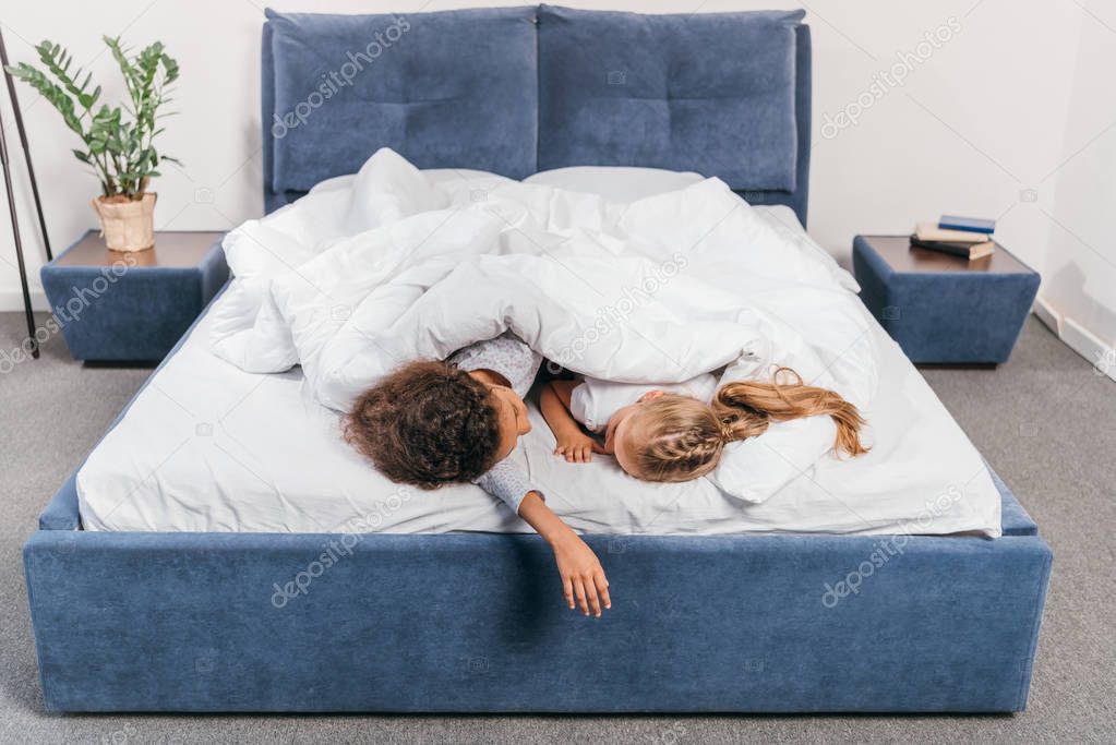 multicultural girls sleeping in bed