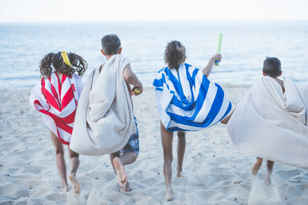 children with towels running on beach