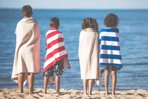 Kids in towels standing on beach — Stock Photo, Image