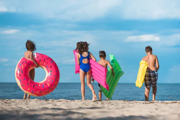Kids with inflatable mattresses on beach — Stock Photo, Image