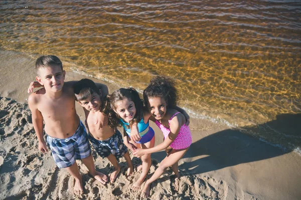 Multicultural kids in swimsuits on beach — Stock Photo, Image