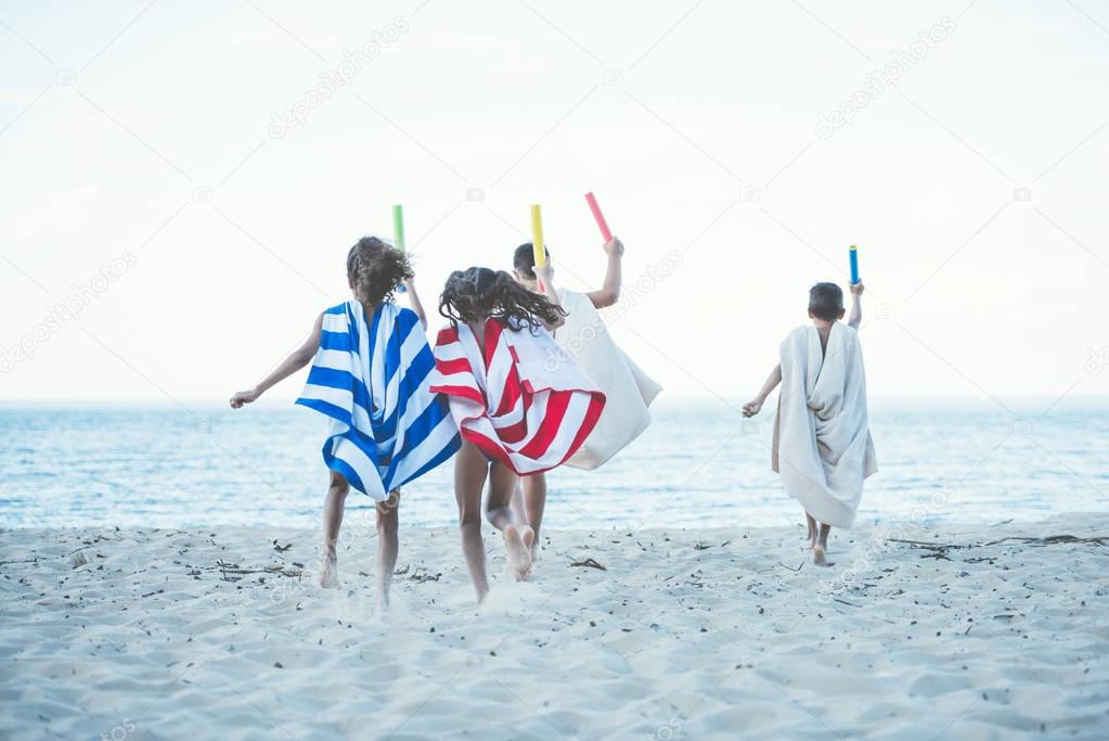 children with towels running on beach