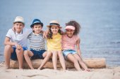 multiethnic children sitting at seaside