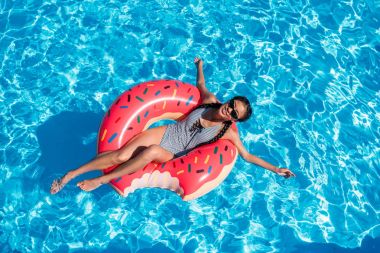 Asian woman on inflatable donut in pool clipart