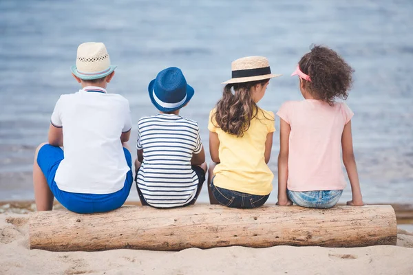 Niños sentados a la orilla del mar — Foto de Stock