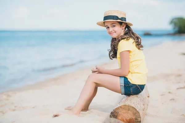 Küçük kız sahilde oturmuş — Stok fotoğraf
