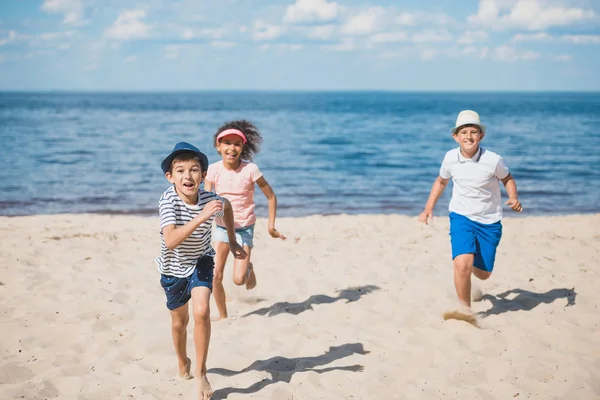 Crianças multiculturais brincando na praia — Fotografia de Stock