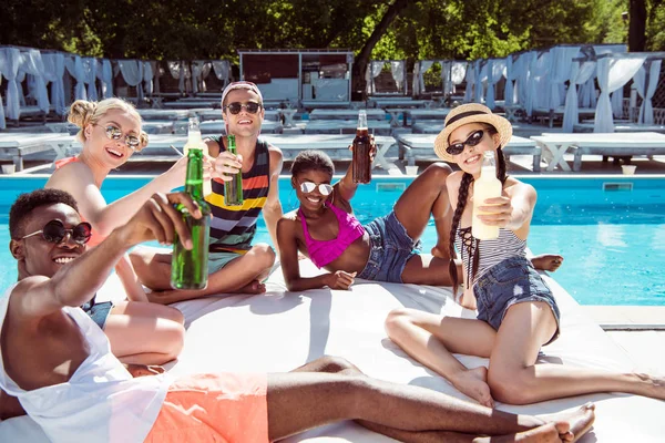 Amigos multiétnicos cerca de la piscina en el resort —  Fotos de Stock