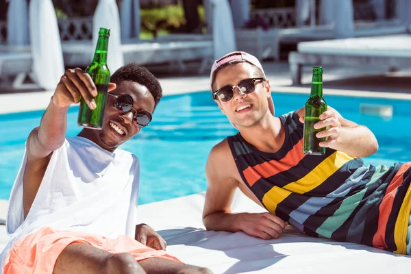 Multiethnic men with beer near pool — Stock Photo, Image