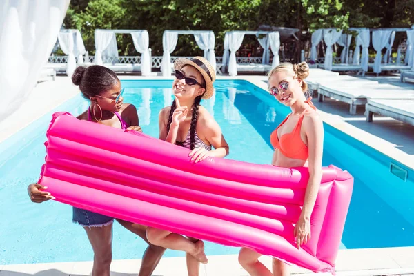 Mujeres multiétnicas con colchón inflable cerca de la piscina —  Fotos de Stock