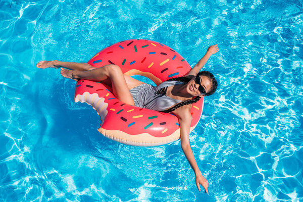 Asian woman on inflatable donut in pool