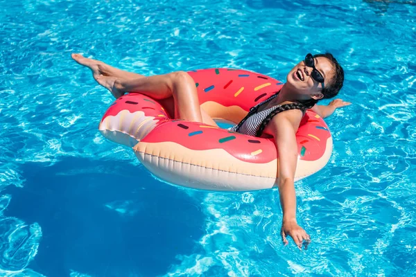 Asiatisk kvinna på uppblåsbara donut i poolen — Stockfoto