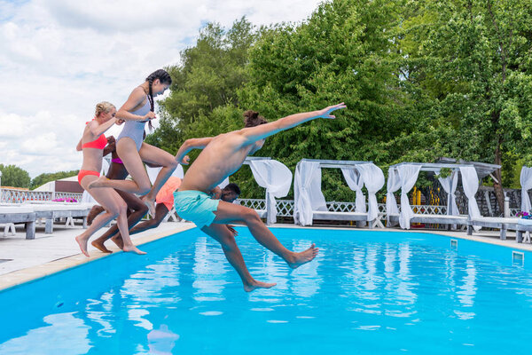 multiethnic people jumping into swimming pool 