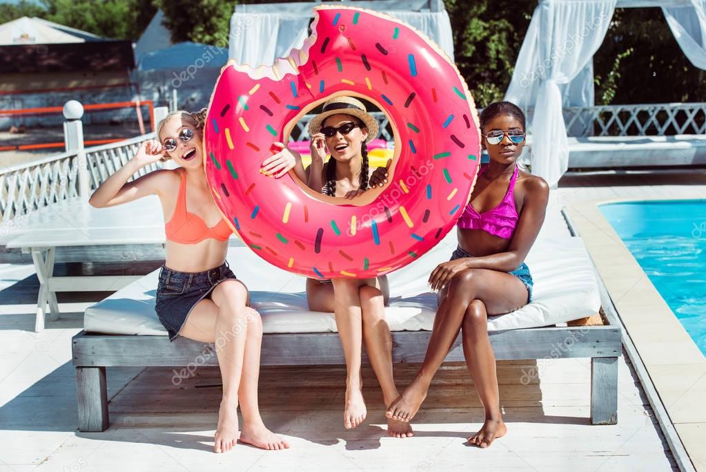 Multiethnic women with inflatable donut near pool