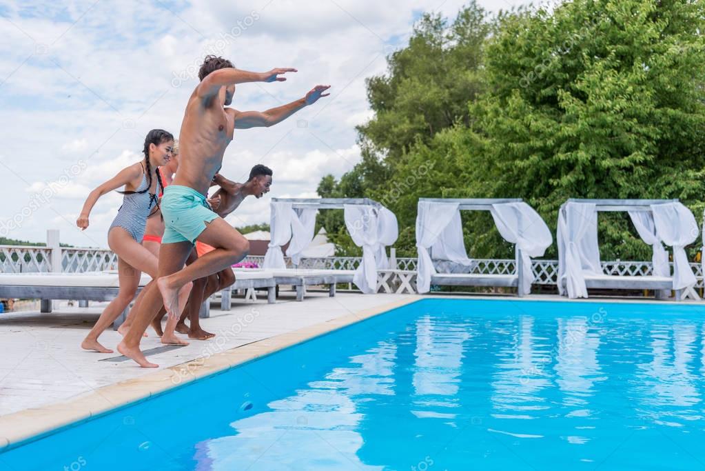 multiethnic people jumping into swimming pool 