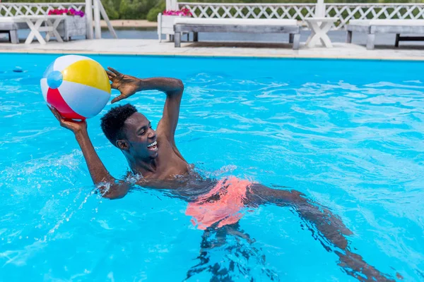 Hombre con pelota en la piscina — Foto de Stock