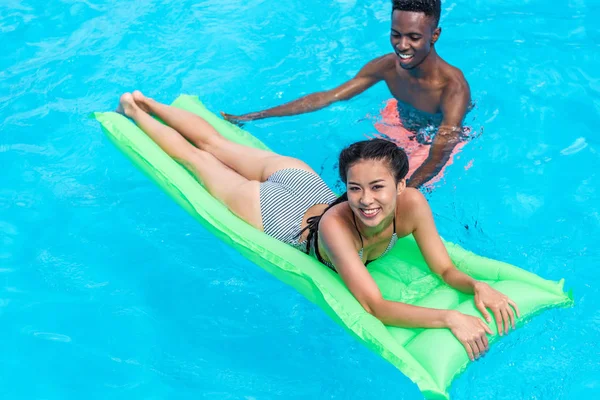 Багатоетнічна пара в басейні на курорті — стокове фото