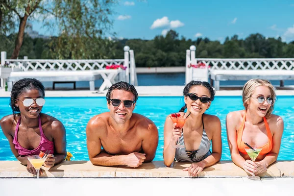 Multiethnische Menschen mit Cocktails im Schwimmbad — Stockfoto