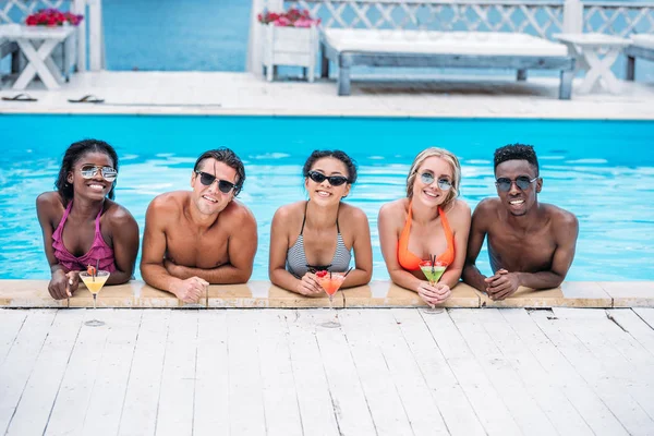 Multiethnische Menschen mit Cocktails im Schwimmbad — Stockfoto